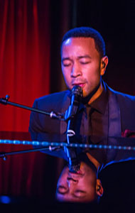 John Legend sitting by Piano